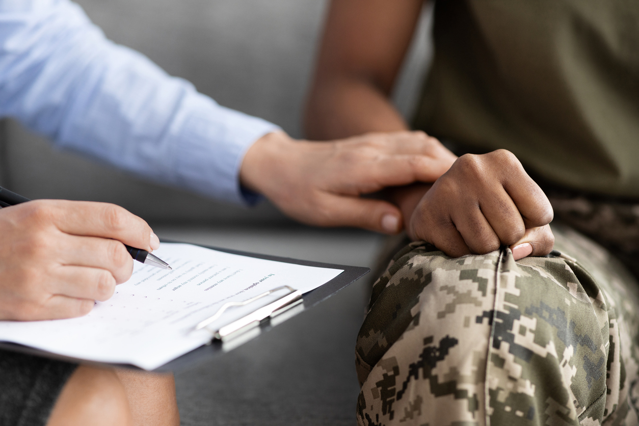 therapist offering comfort to a person in military uniform during a ptsd treatment session.